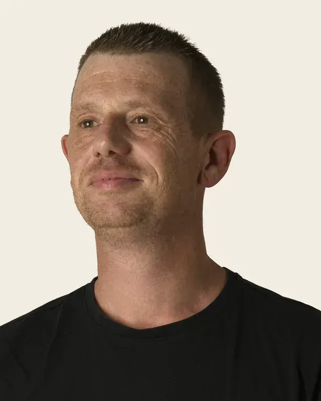 Portret van Brian van Straalen, in zwart T-shirt, tegen een effen lichte achtergrond.