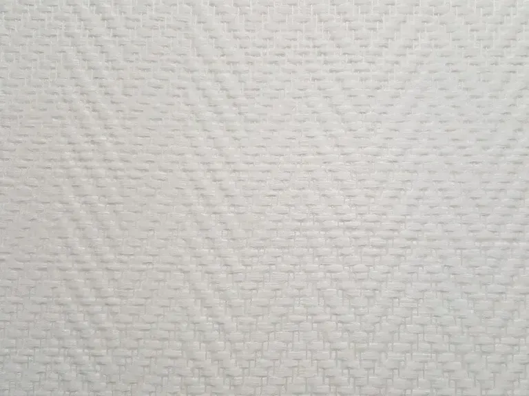Wit glasweefselbehang van dichtbij met een geweven visgraatstructuur.